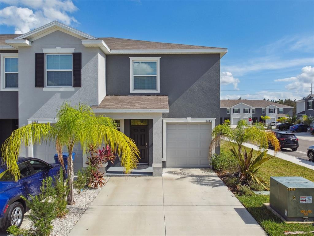 A two-story townhouse with a gray stucco exterior, a single-car garage, and a concrete driveway — 2880 EVERGREEN ELM PASS, WESLEY CHAPEL, FL