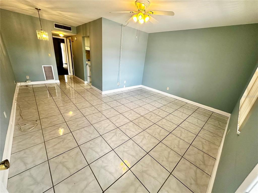 An empty room with light blue walls, large square floor tiles, and a ceiling fan — 4742 AZALEA DRIVE UNIT 205, NEW PORT RICHEY, FL