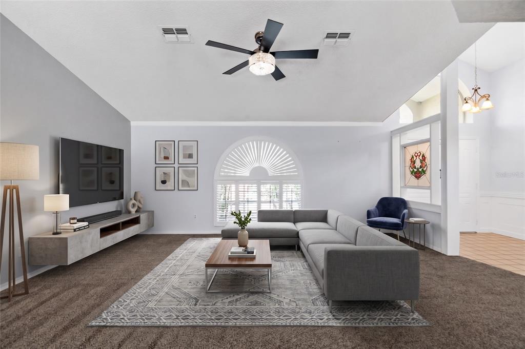 A living room features a gray sectional sofa, a wall-mounted media console, and carpeted floors — 1174 MUSCOVY DRIVE, SPRING HILL, FL