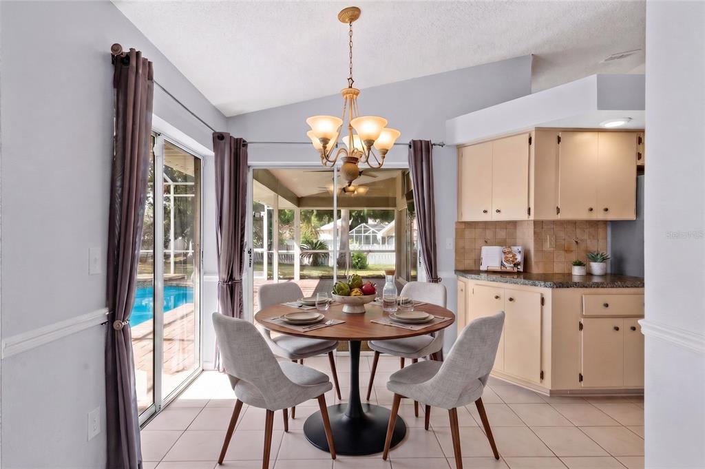 A dining area features a round table, four chairs, a chandelier, and sliding glass doors — 1174 MUSCOVY DRIVE, SPRING HILL, FL