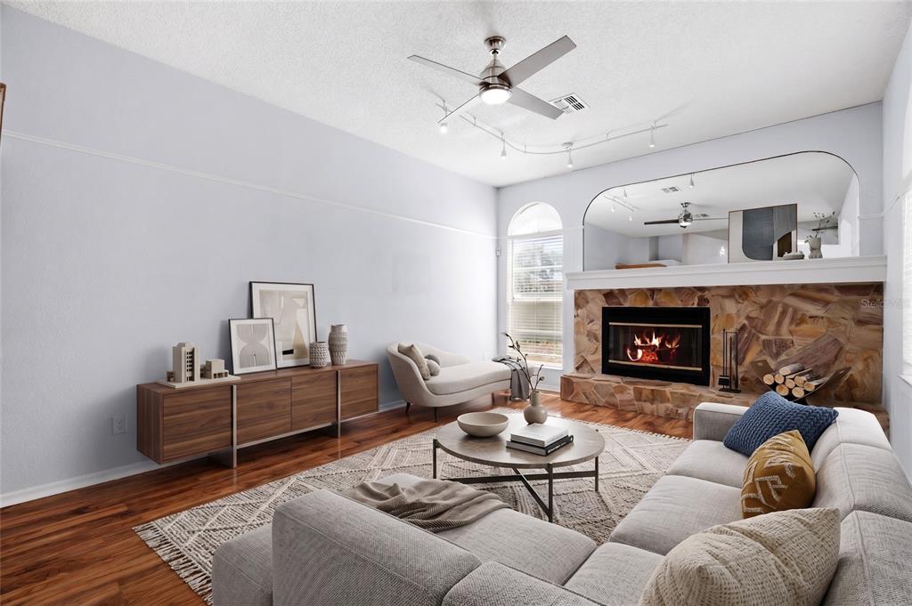 A living room features a stone fireplace, a large mirror, a ceiling fan, and hardwood floors — 1174 MUSCOVY DRIVE, SPRING HILL, FL