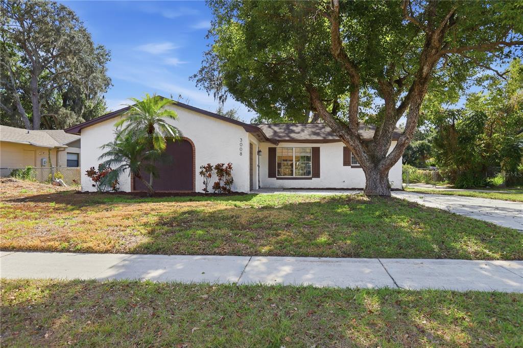 A single-story house with a white stucco exterior, a brown roof, and a large tree — 3008 CALUMET DRIVE, ORLANDO, FL