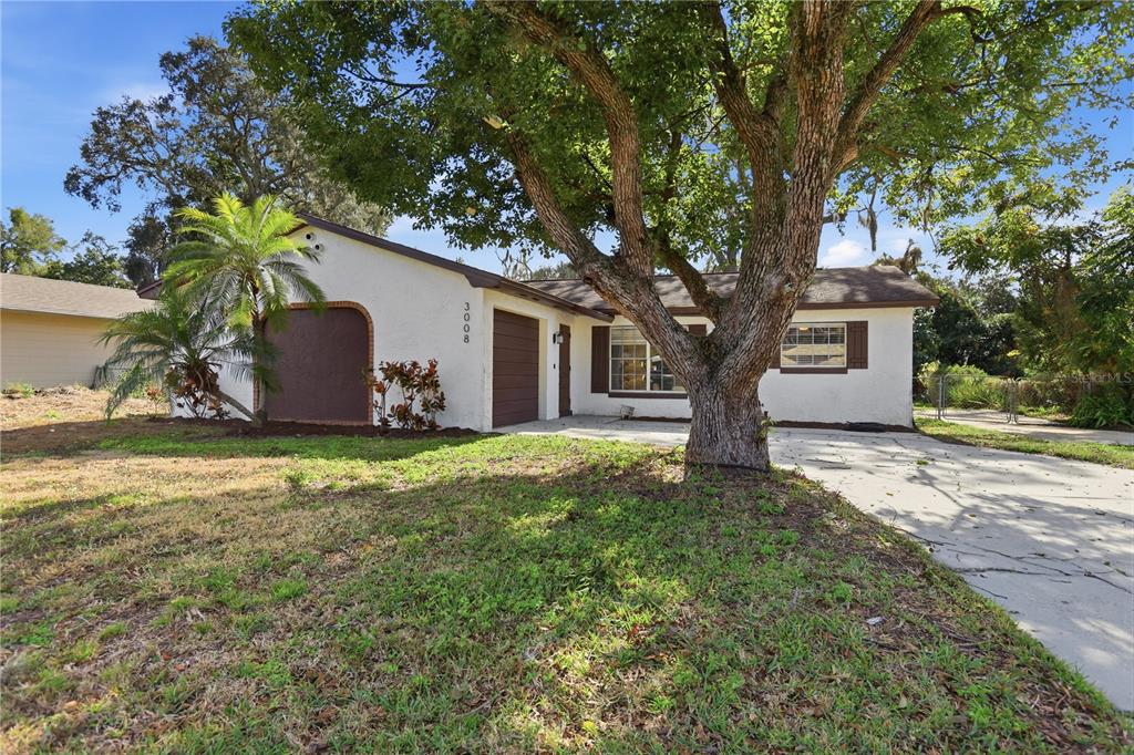 A single-story house with a white exterior, a brown garage door, and a large tree — 3008 CALUMET DRIVE, ORLANDO, FL