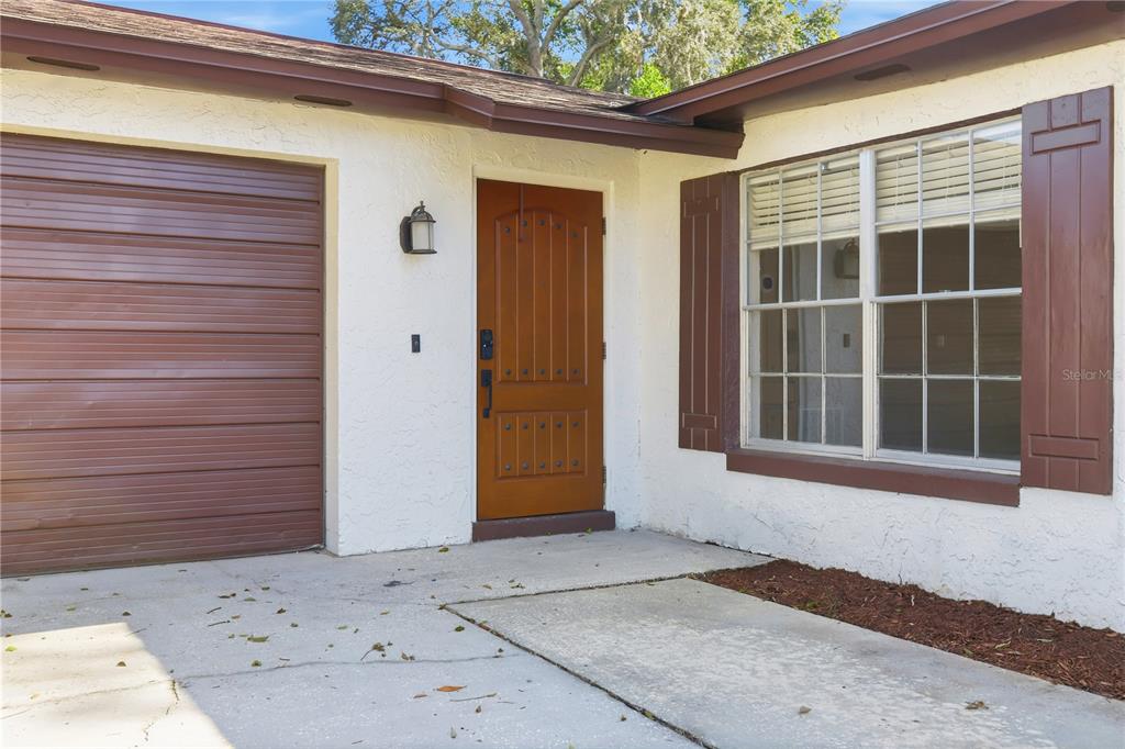 The exterior view shows a white stucco house with a brown garage door and door — 3008 CALUMET DRIVE, ORLANDO, FL