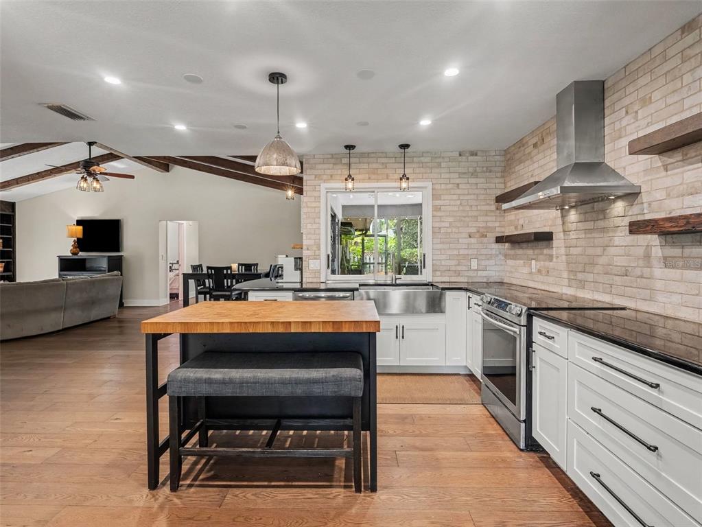 A kitchen with white cabinets, a wood-topped island, and a brick backsplash — 3911 COUNTRY VIEW CIR, SARASOTA, FL