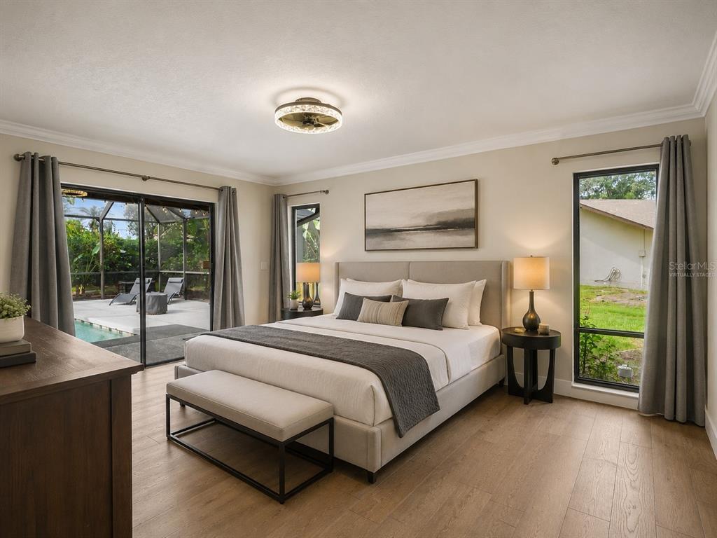 A bedroom with a bed, bench, and sliding glass doors leading to a pool patio — 3911 COUNTRY VIEW CIR, SARASOTA, FL
