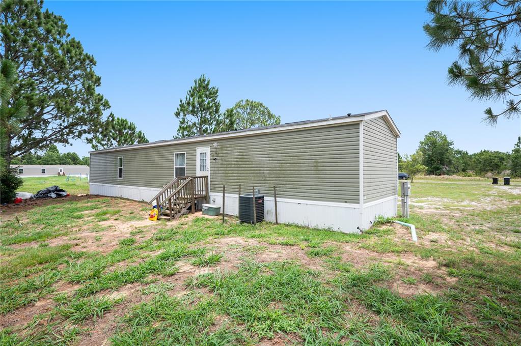 The exterior of a single-wide mobile home with green siding sits on a grassy lot — 4770 SUGARFOOT AVENUE, LAKE WALES, FL