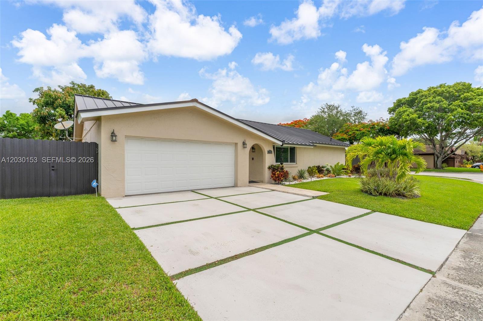 A single-story house features a tan exterior, a metal roof, and a concrete driveway — 11375 SW 113th Ter, Miami FL 33176, MIAMI, FL