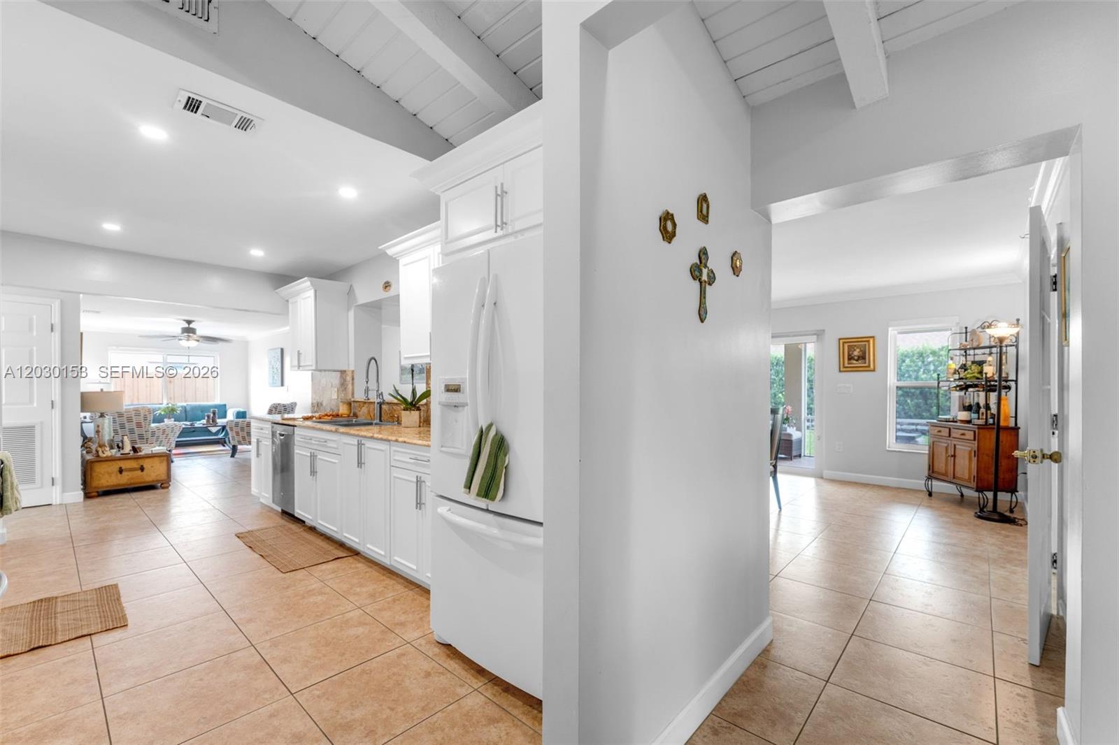 A white kitchen with tile floors opens into a living area with vaulted ceilings — 11375 SW 113th Ter, Miami FL 33176, MIAMI, FL