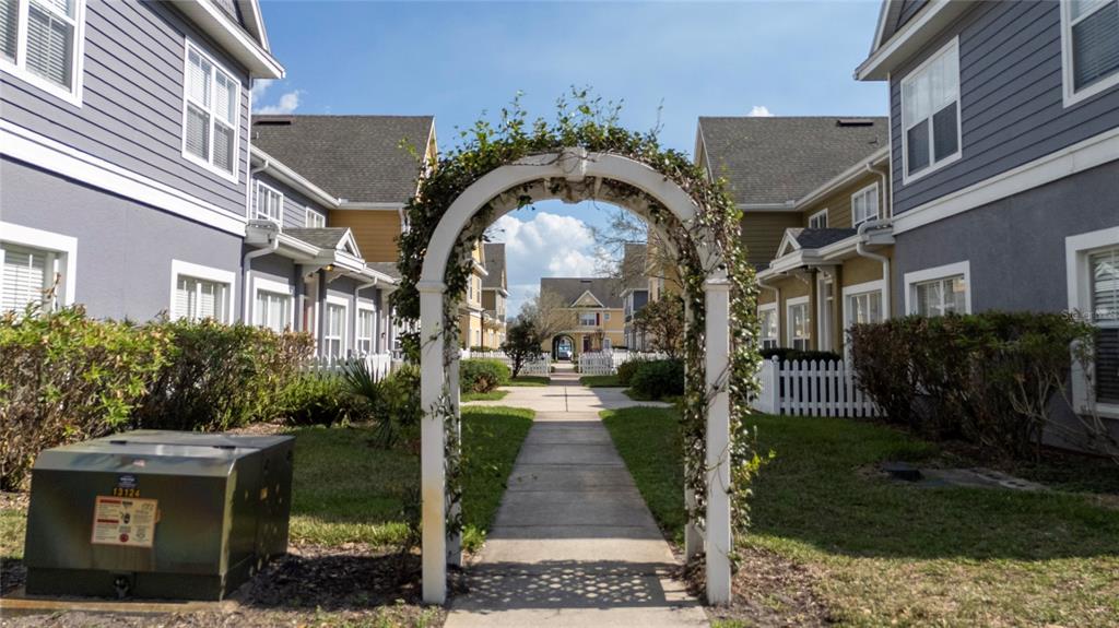 A two-story townhouse exterior features a red front door, white trim, and small picket fences — 2611 GALA ROAD N UNIT 106, KISSIMMEE, FL