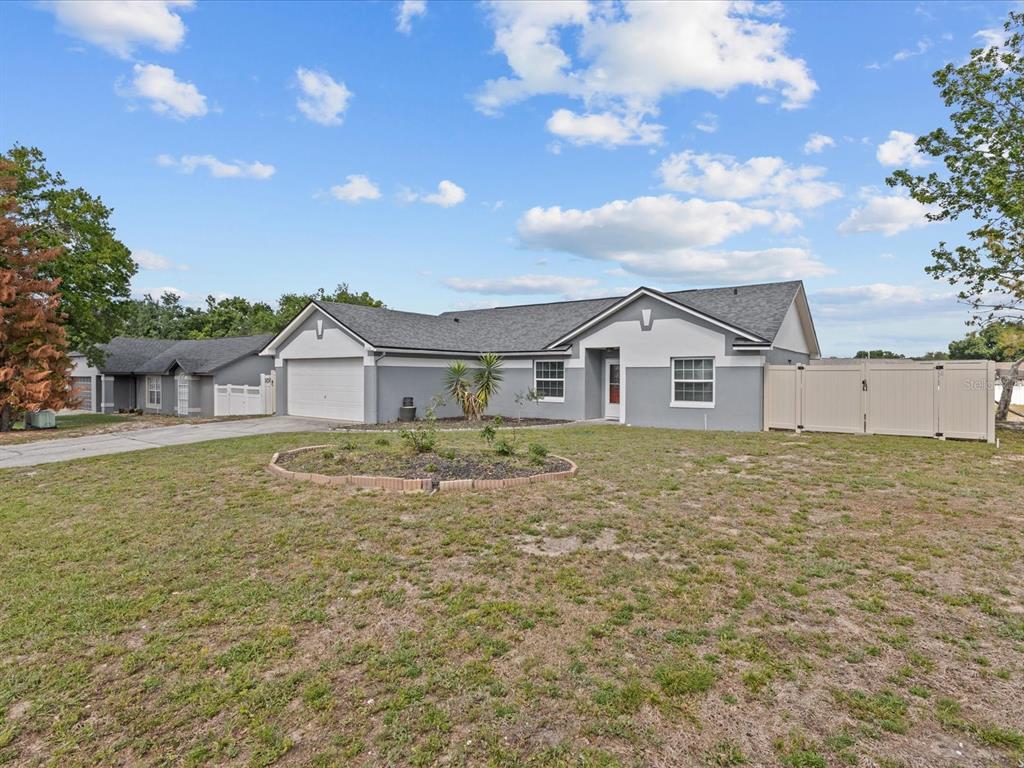 A single-story gray house with a two-car garage and a front yard garden bed — 226 WINDWARD WAY, DAVENPORT, FL
