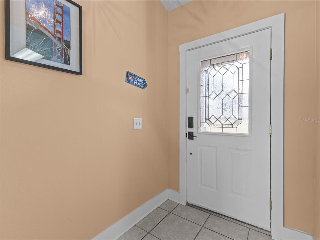 An entryway features a white front door with a decorative glass insert and tiled flooring — 226 WINDWARD WAY, DAVENPORT, FL