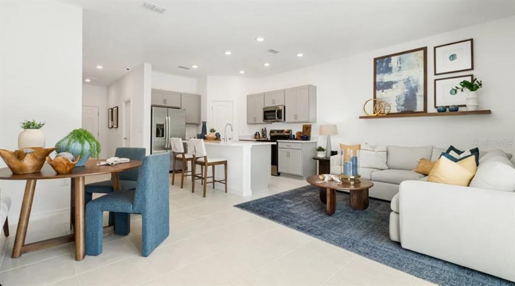 A living room features a white sectional sofa, a round wooden coffee table, and wall art — 7162 GRAND FOREST WAY, NOKOMIS, FL