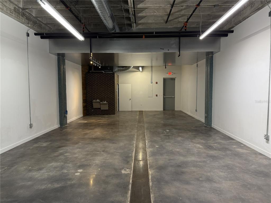 An empty commercial space features a concrete floor, white walls, and exposed ceiling utilities — 302 SE BROADWAY STREET UNIT 110, OCALA, FL