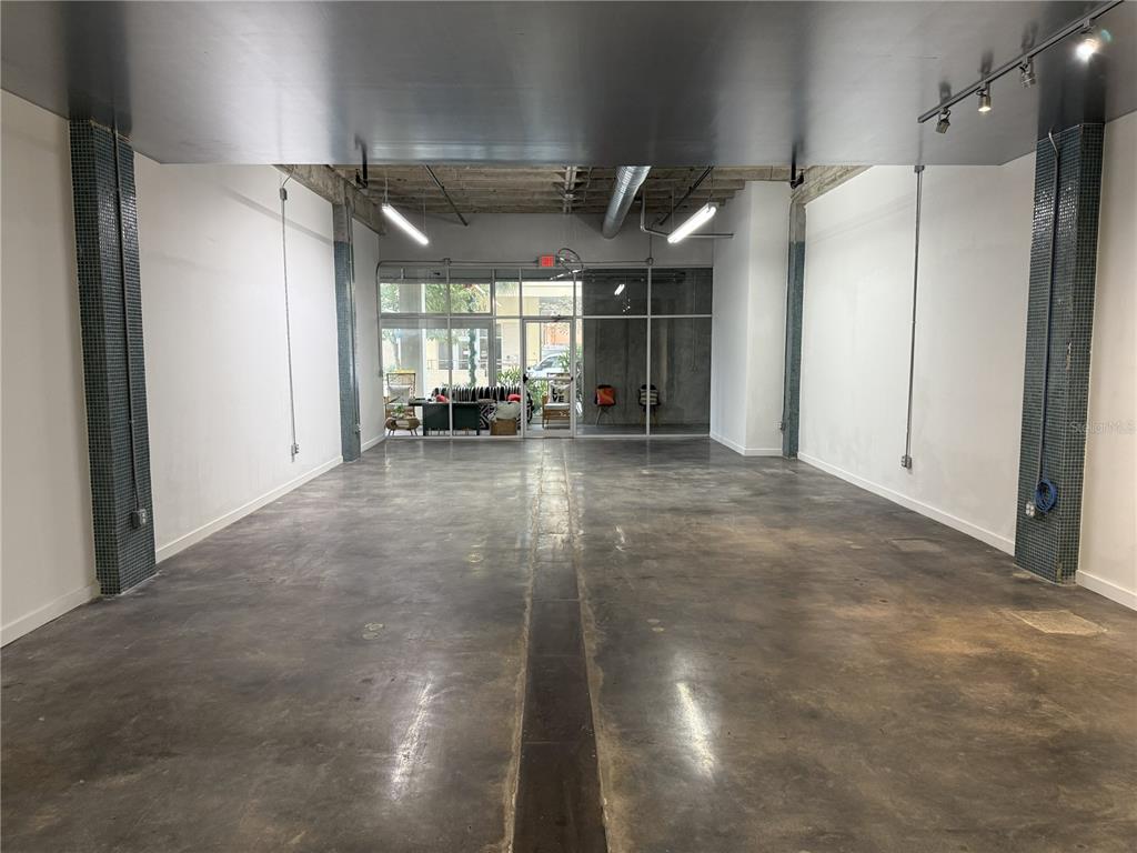 An empty commercial space features concrete floors, white walls, exposed ceiling ducts, and tiled columns — 302 SE BROADWAY STREET UNIT 110, OCALA, FL