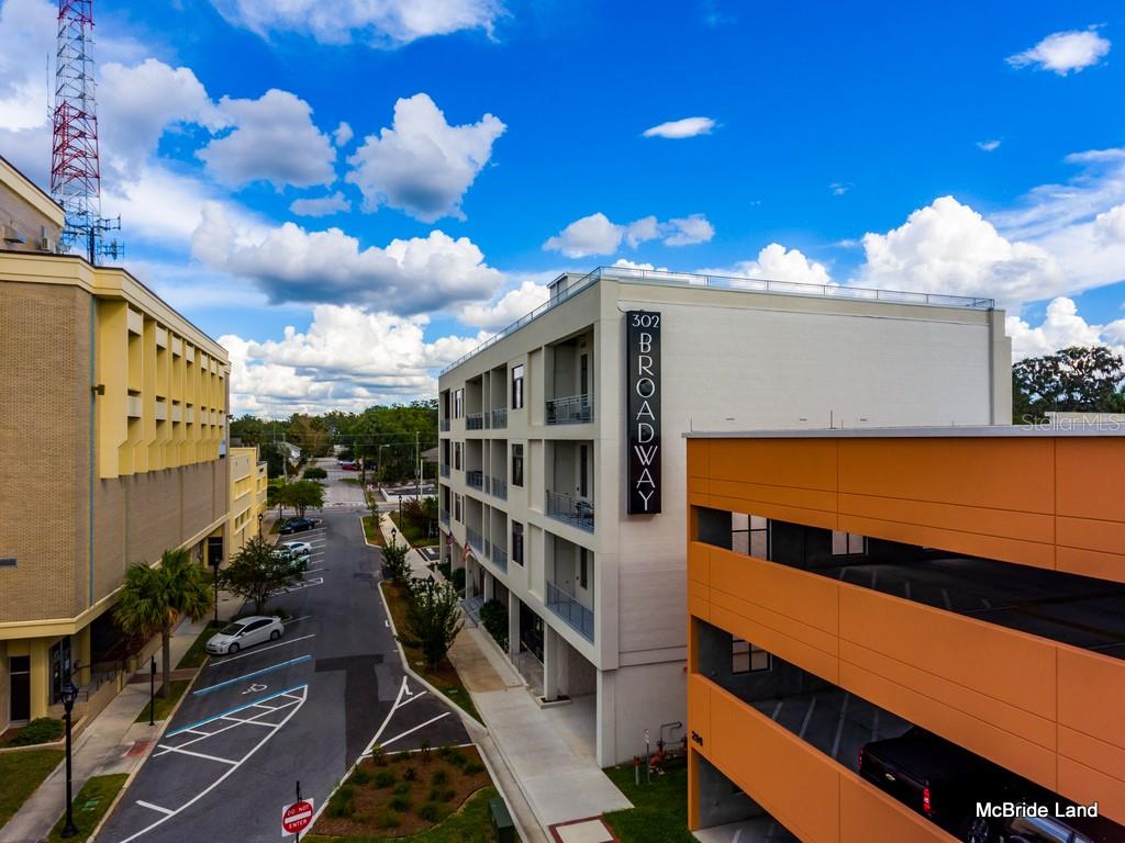 An exterior view shows a modern apartment building next to a parking garage and street — 302 SE BROADWAY STREET UNIT 110, OCALA, FL