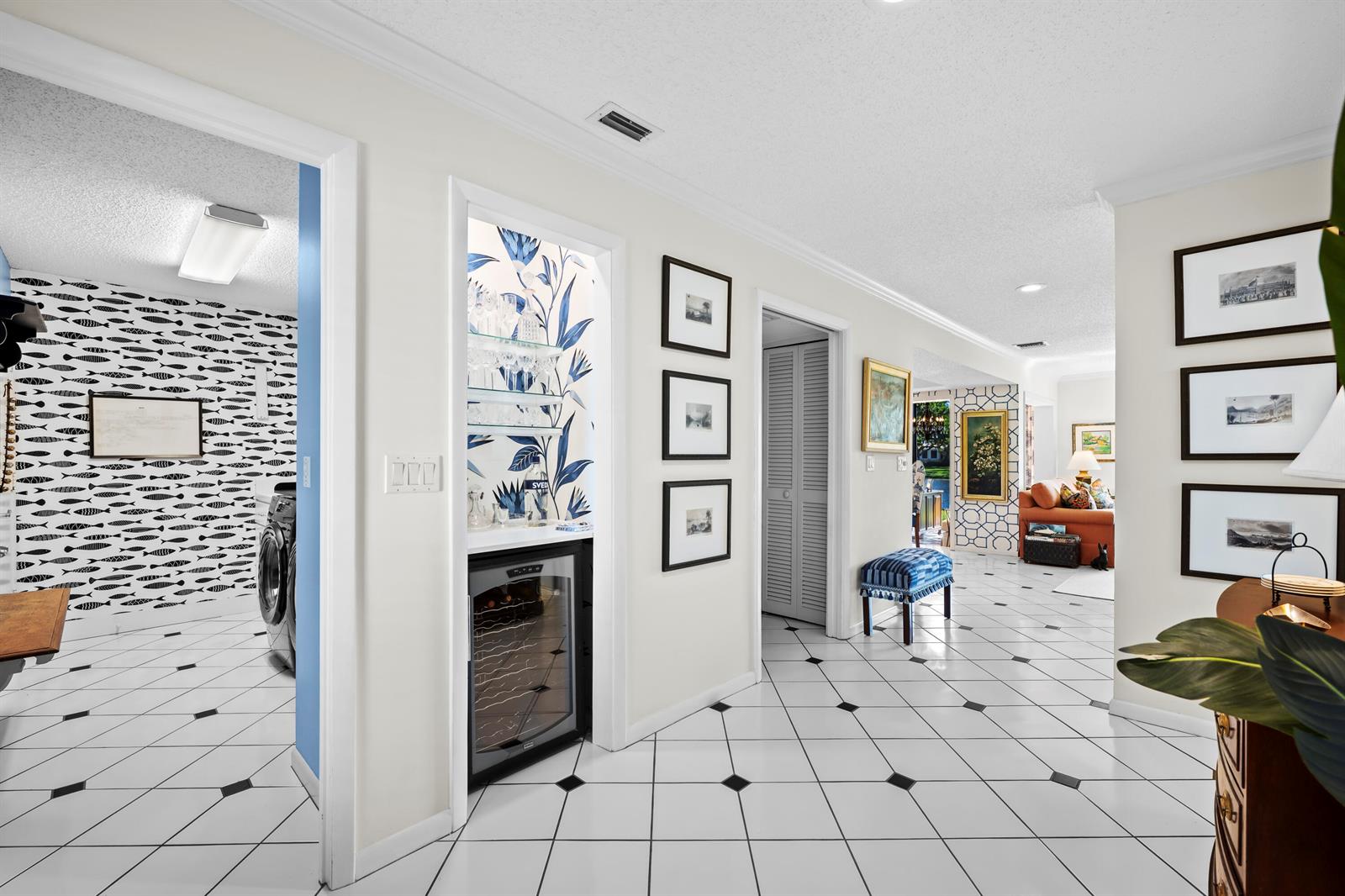 A hallway with white and black tile flooring leads to a living area and bar — 5610 SE Foxcross Place, Stuart FL 34997, STUART, FL