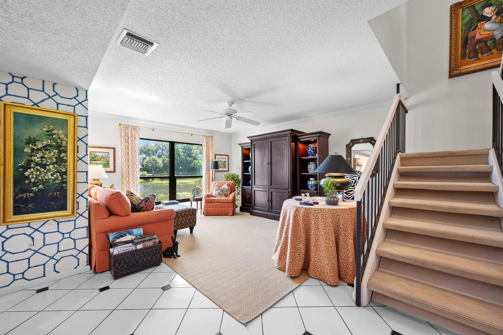 A living room features a staircase, a large entertainment center, and a view of water — 5610 SE Foxcross Place, Stuart FL 34997, STUART, FL