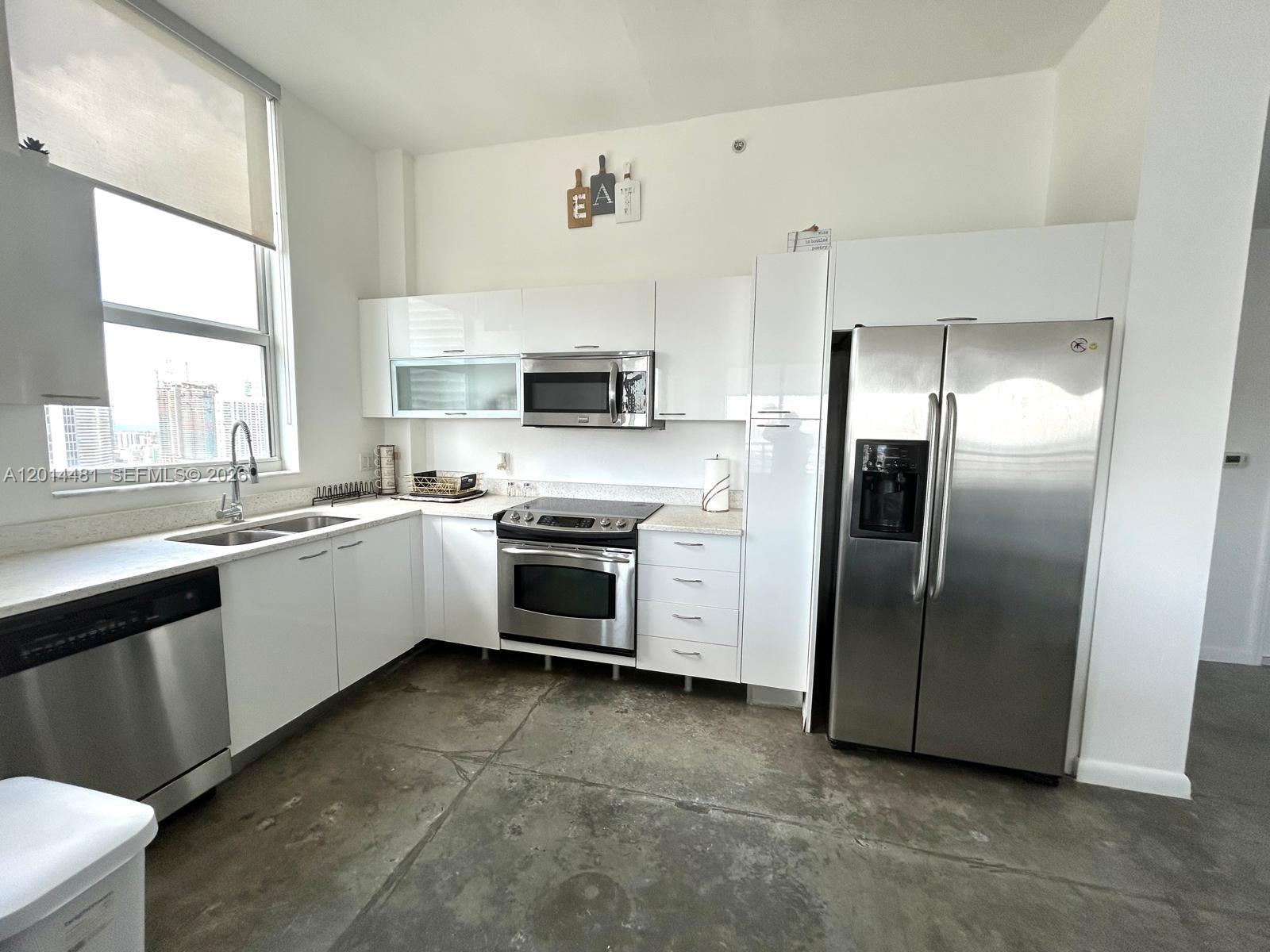 A modern kitchen features white cabinets, stainless steel appliances, and a concrete floor — 133 NE 2nd Ave # 3202, Miami FL 33132, MIAMI, FL