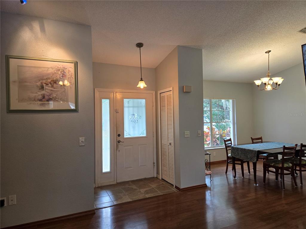 An entryway with a front door, tile flooring, and an adjacent dining area with wood floors — 7605 LANDMARK DRIVE, SPRING HILL, FL