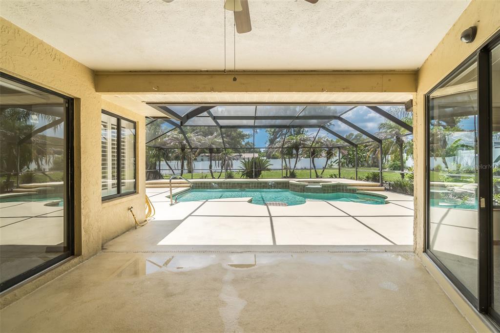 A covered patio looks out onto a screened-in swimming pool and backyard — 714 PENNYROYAL PLACE, BRANDON, FL