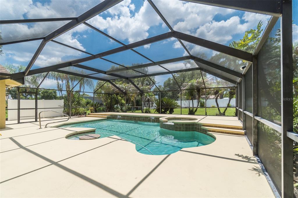 A screened-in swimming pool and spa with a concrete deck under a metal frame enclosure — 714 PENNYROYAL PLACE, BRANDON, FL