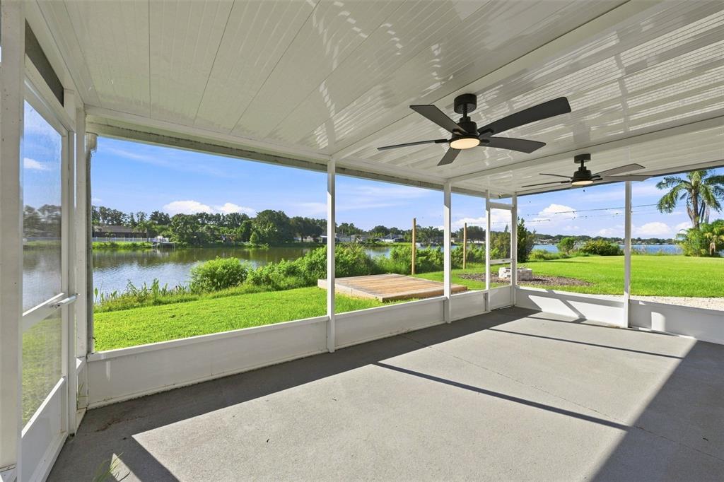 A screened-in patio with concrete flooring, two ceiling fans, and a view of a lake — 6505 CLAIR NEST COURT, APOLLO BEACH, FL