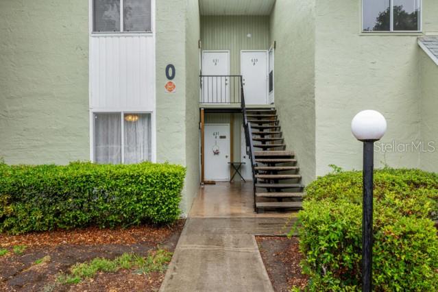 An exterior view of a two-story apartment building with a central staircase and landscaping — 631 SILVER PASS UNIT A, OCALA, FL
