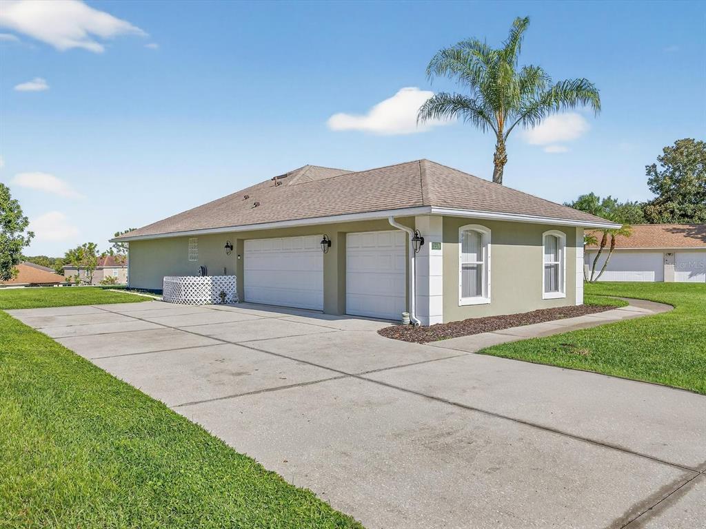 A side view of a house with a two-car garage and a concrete driveway — 11519 GRAND BAY BOULEVARD, CLERMONT, FL