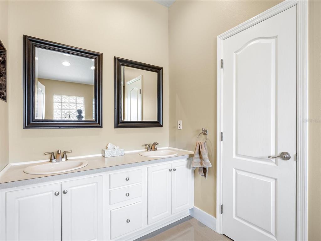 A walk-in shower features large beige tiles, a mosaic accent strip, and dual showerheads — 11519 GRAND BAY BOULEVARD, CLERMONT, FL