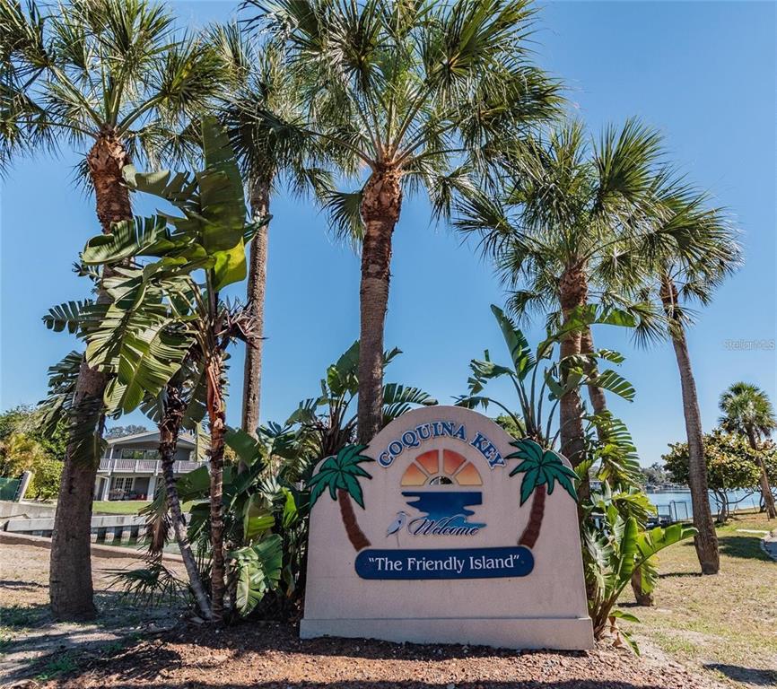 A sign for Coquina Key stands outdoors surrounded by palm trees and tropical plants — 4200 BLUEFISH DRIVE SE, ST PETERSBURG, FL