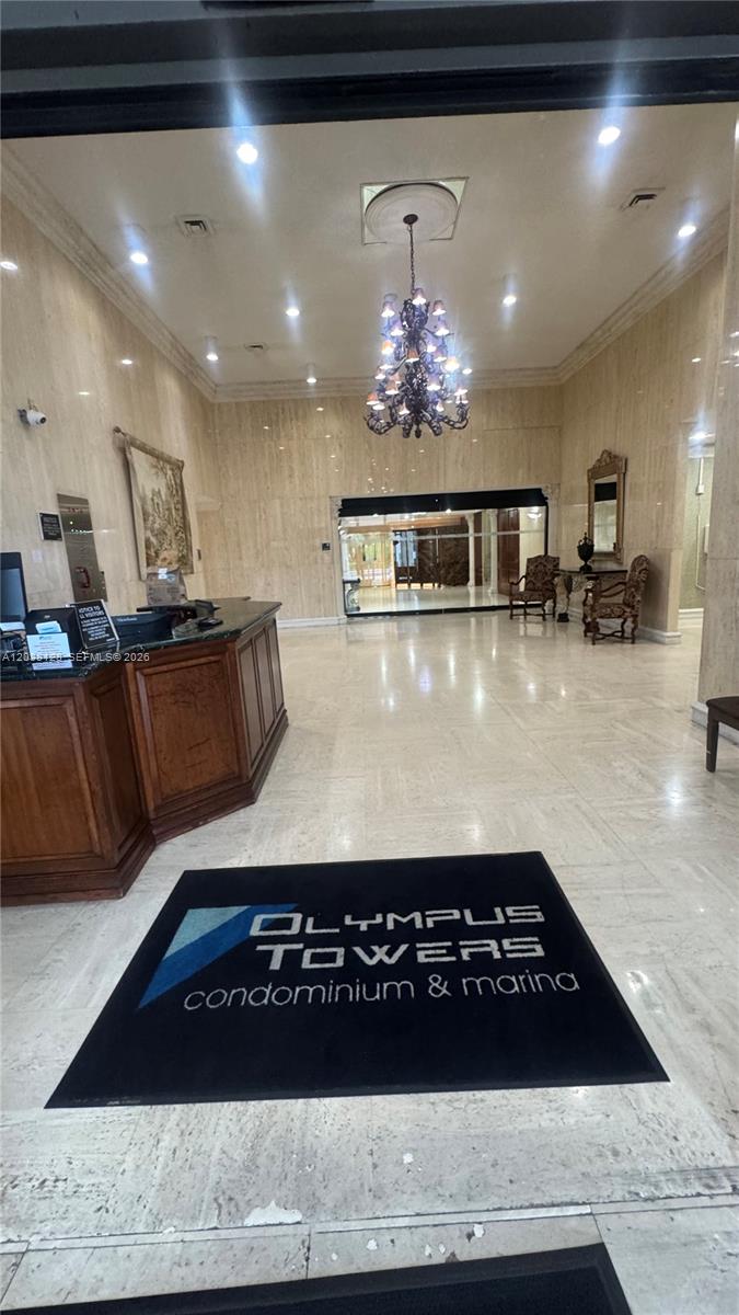 The lobby of a condominium building features a reception desk, chandelier, and marble flooring — HALLANDALE BEACH, FL