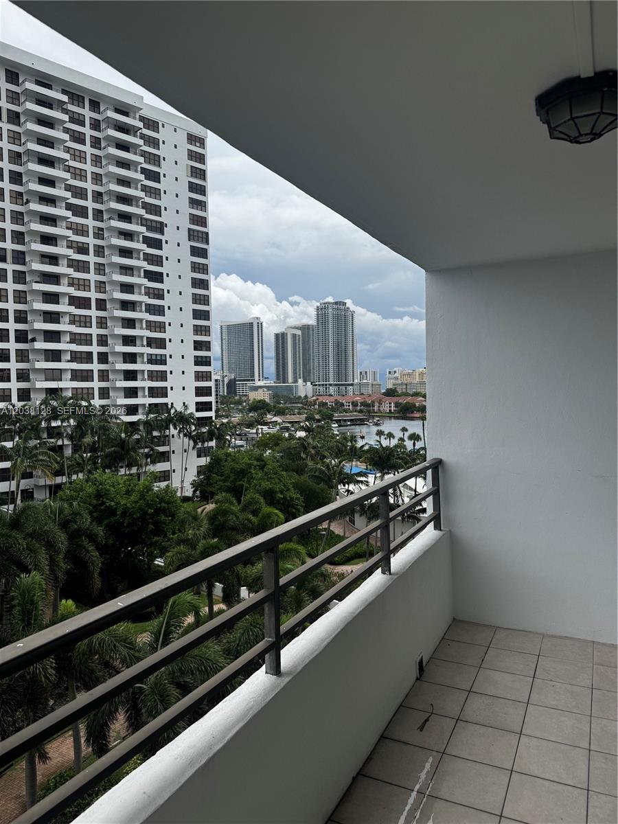 A balcony with a metal railing overlooks a canal, palm trees, and distant city high-rises — HALLANDALE BEACH, FL