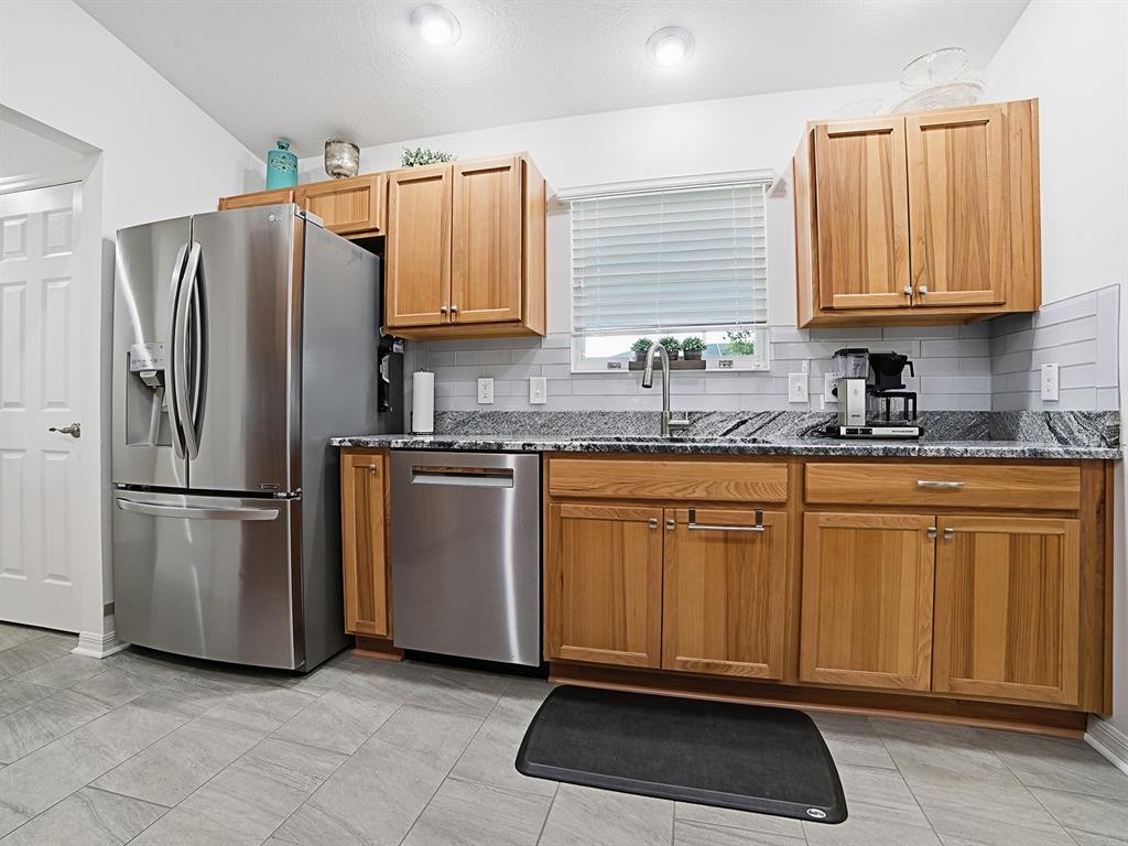 A kitchen features wood cabinets, stainless steel appliances, granite countertops, and a gray tile floor — 843 CLIFFORD COURT, THE VILLAGES, FL