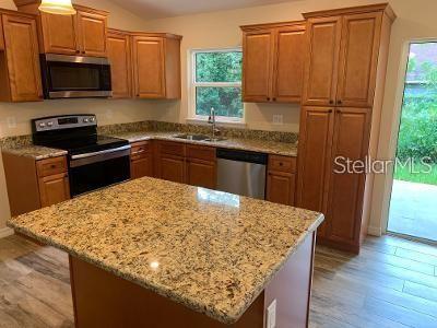 A kitchen features wood cabinets, granite countertops, stainless steel appliances, and a central island — 1295 12TH STREET, ORANGE CITY, FL