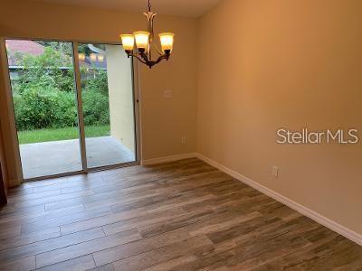 A dining area with wood-look tile flooring, a chandelier, and a sliding glass door — 1295 12TH STREET, ORANGE CITY, FL