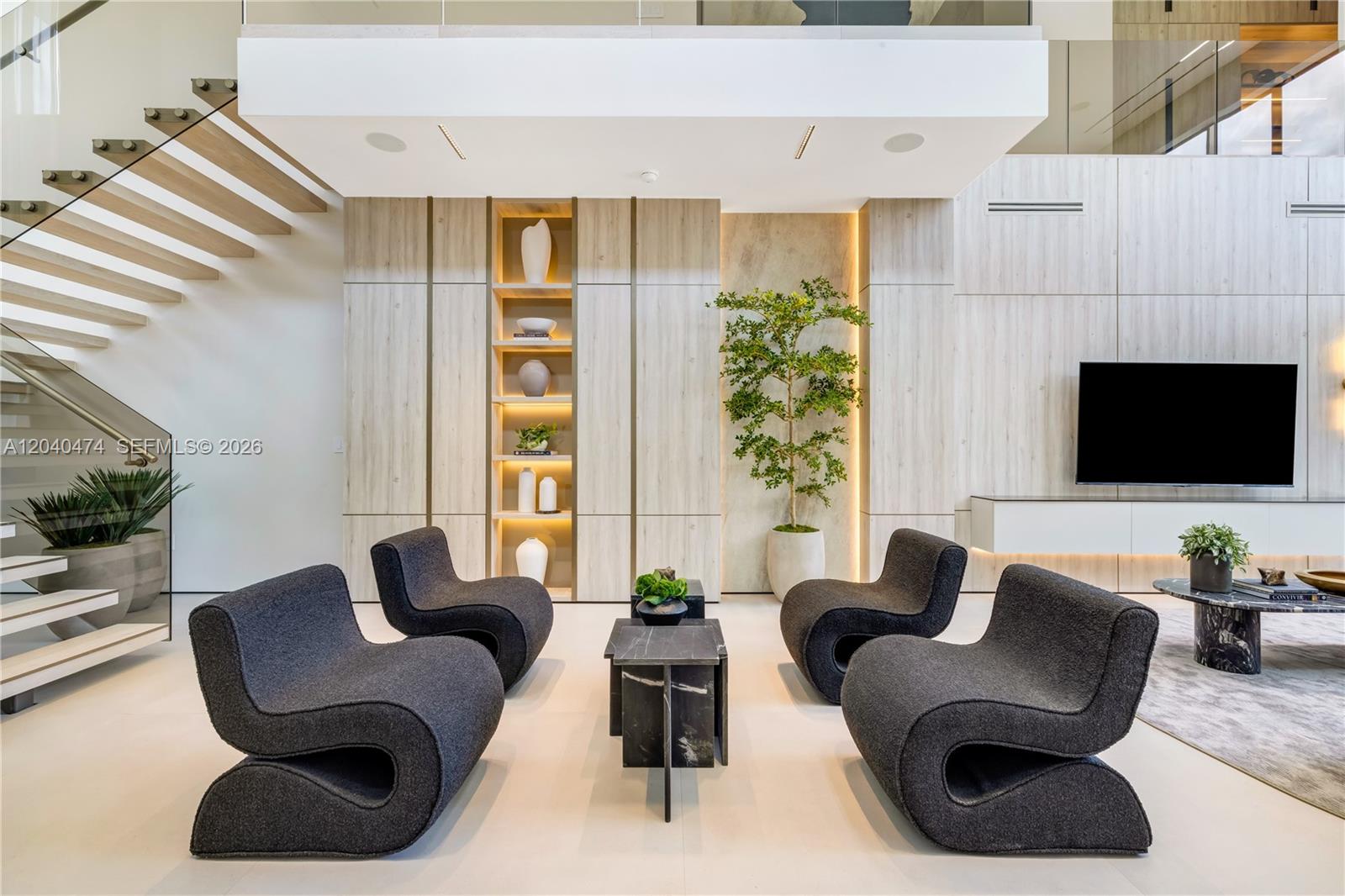 A modern living room features four dark sculptural chairs, a marble coffee table, and wood-paneled walls — 1008 NE 114th St, Biscayne Park FL 33161, BISCAYNE PARK, FL