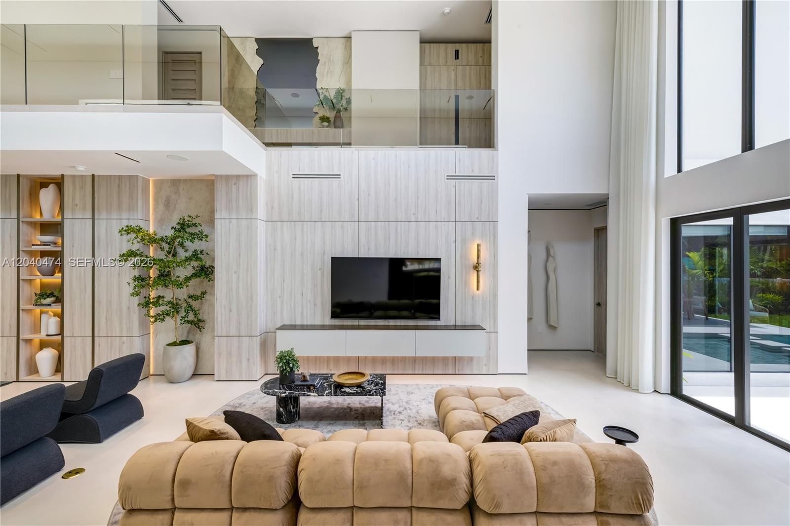 A modern living room features a double-height ceiling, wood-paneled walls, and a large sectional sofa — 1008 NE 114th St, Biscayne Park FL 33161, BISCAYNE PARK, FL