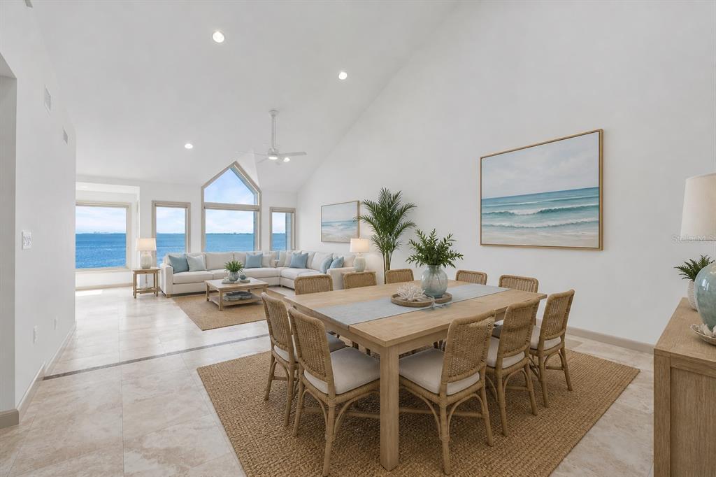 A bright, open-concept living and dining area features vaulted ceilings, coastal decor, and ocean views — 24 TIDY ISLAND BOULEVARD, BRADENTON, FL