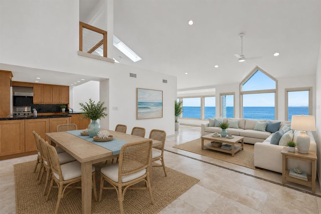 An open-concept living and dining area features light wood furniture, tile floors, and ocean views — 24 TIDY ISLAND BOULEVARD, BRADENTON, FL