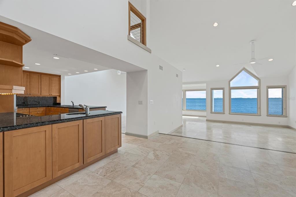 A kitchen with wood cabinets and granite countertops overlooks a living area with ocean views — 24 TIDY ISLAND BOULEVARD, BRADENTON, FL