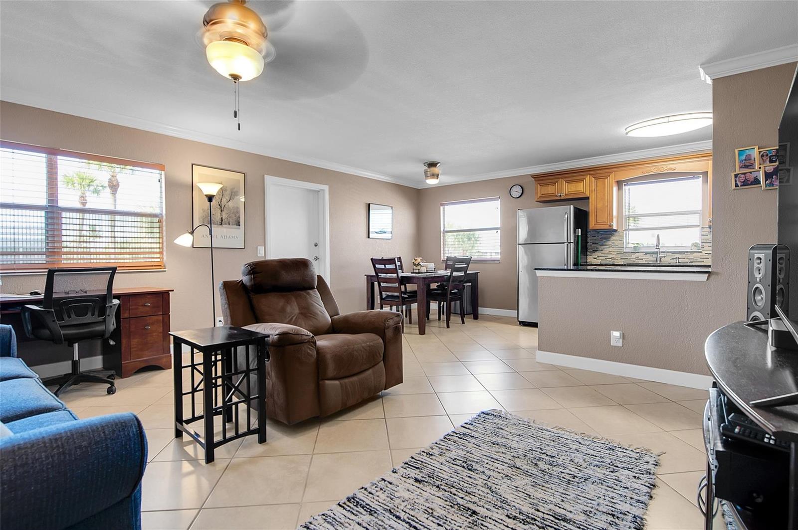 An open-concept living and dining area features tile flooring, a brown recliner, and a kitchen — 409 Brittany I # 409, Delray Beach FL 33446, DELRAY BEACH, FL