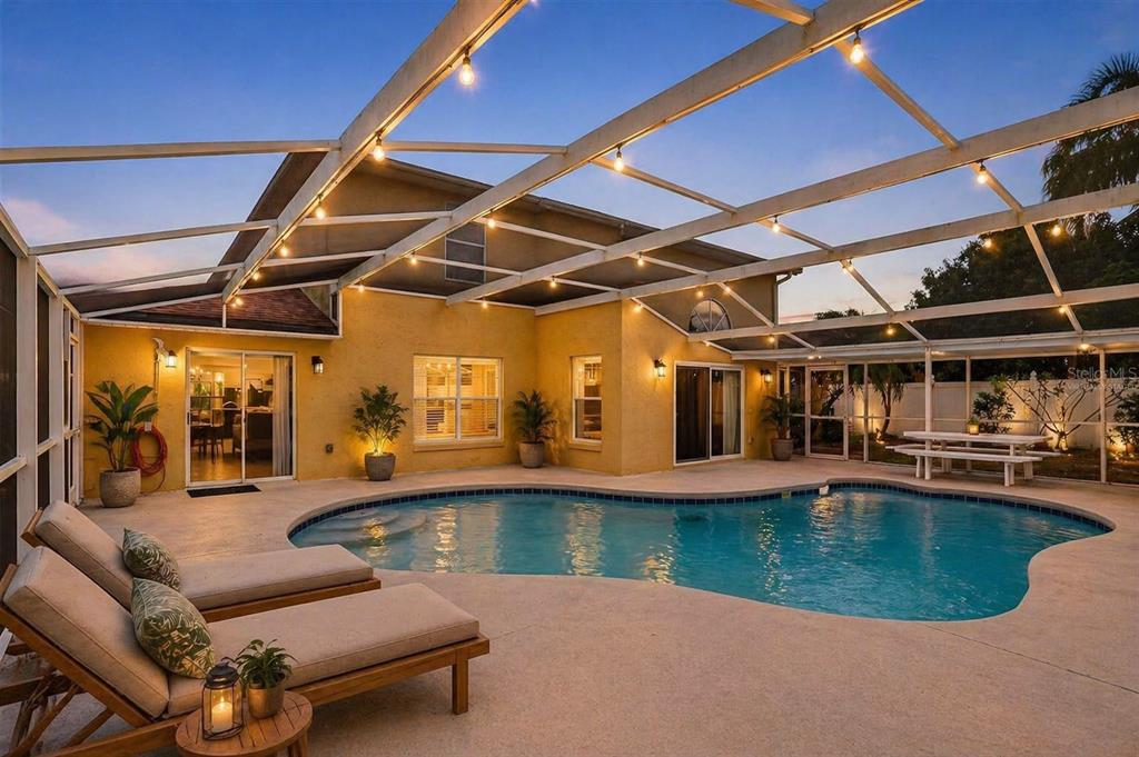 A swimming pool with a screened enclosure and lounge chairs on a concrete patio — 14912 WHITE MAGNOLIA COURT, ORLANDO, FL