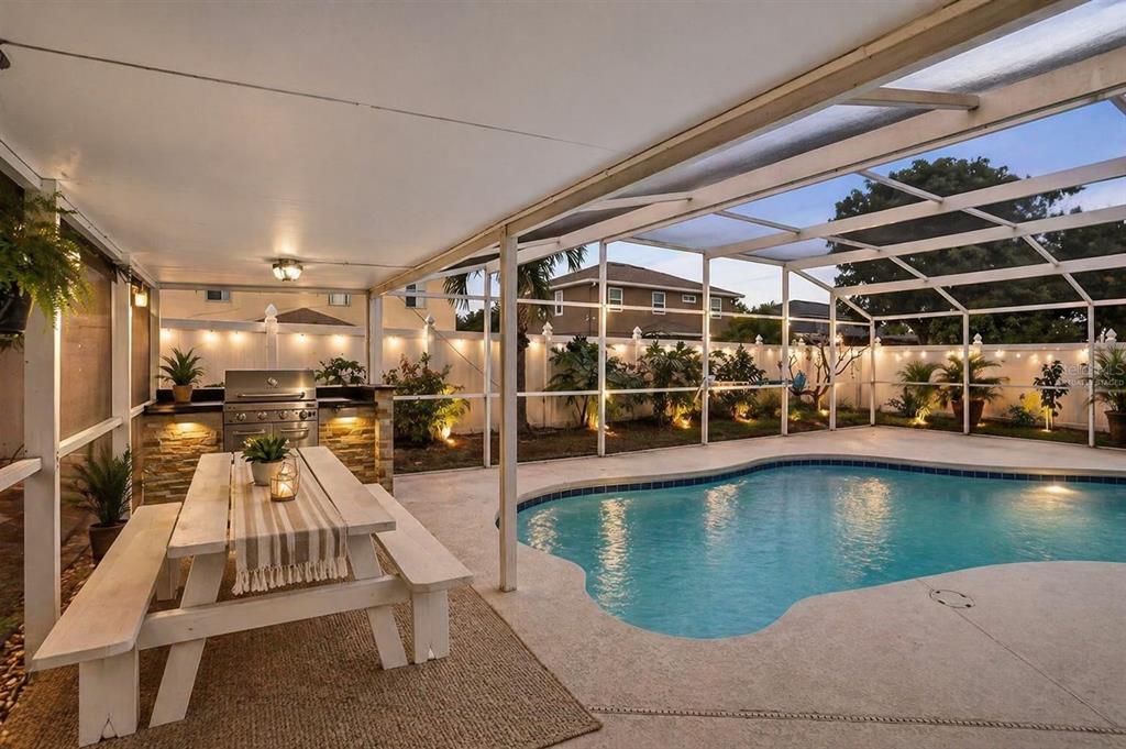 A screened-in patio features a dining table, outdoor kitchen, and a swimming pool — 14912 WHITE MAGNOLIA COURT, ORLANDO, FL