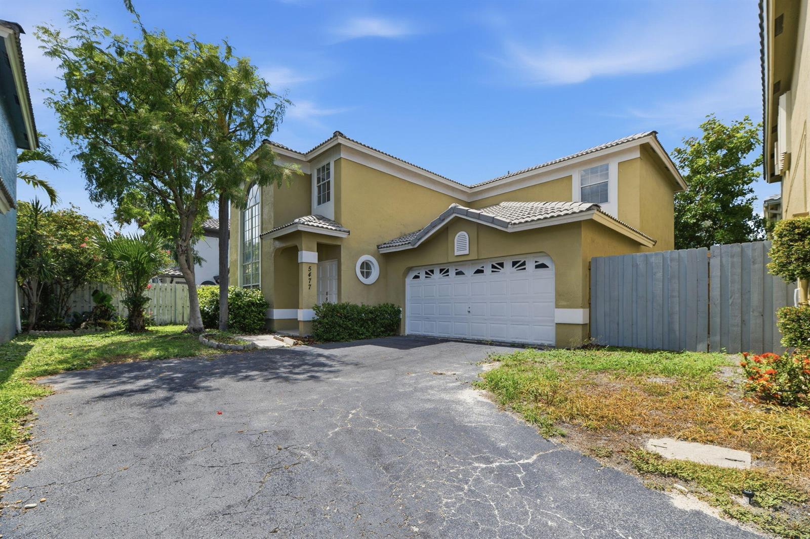 A two-story yellow house with a white garage door and a paved driveway — 5477 NW 44th Way, Coconut Creek FL 33073, COCONUT CREEK, FL