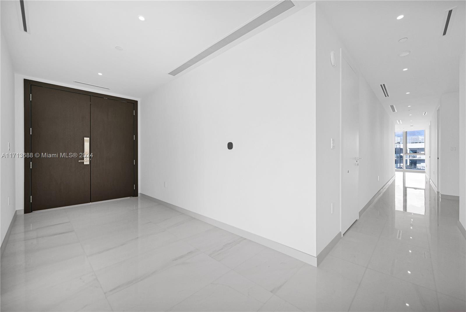 A minimalist entryway features dark double doors, white walls, and polished light-colored tile flooring — 300 Biscayne Blvd Way # 4303, Miami FL 33131, MIAMI, FL