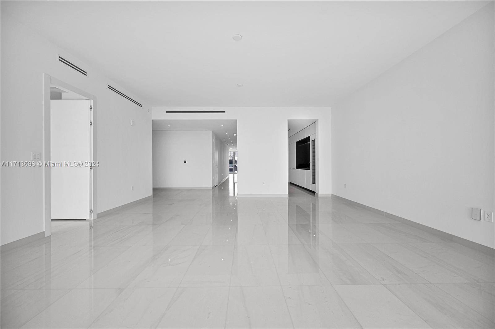 A minimalist, empty room features white walls, recessed lighting, and polished light-colored tile flooring — 300 Biscayne Blvd Way # 4303, Miami FL 33131, MIAMI, FL