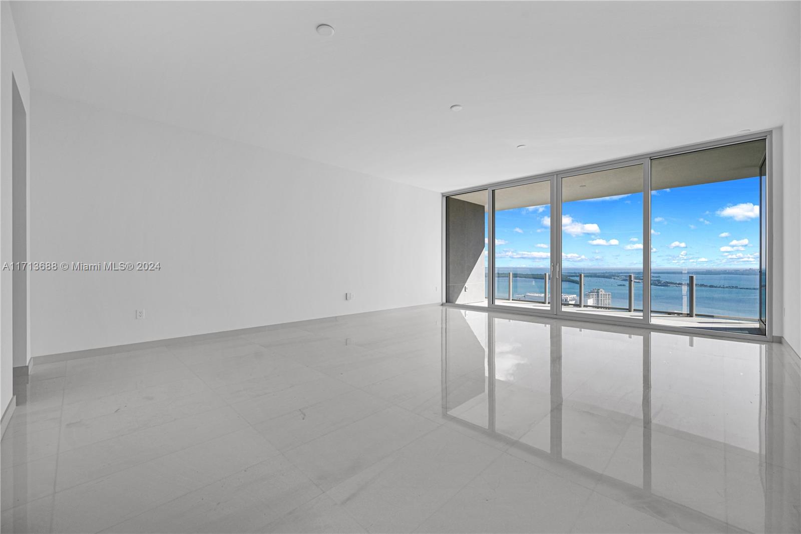 An empty room with white walls, glossy tile floors, and floor-to-ceiling windows overlooking the ocean — 300 Biscayne Blvd Way # 4303, Miami FL 33131, MIAMI, FL
