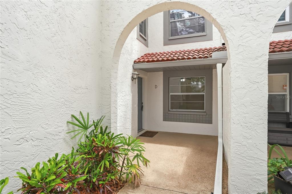 An arched entryway leads to the front door of a white stucco townhouse unit — 500 SANTA CRUZ PLACE NE UNIT D, ST PETERSBURG, FL