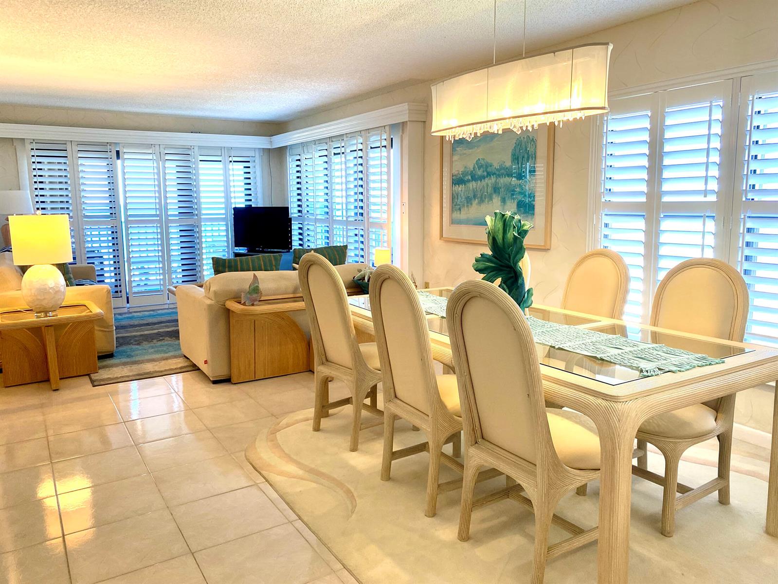 A dining area with a glass-top table and chairs sits adjacent to a living room — 10200 S Ocean Drive # 710, Jensen Beach FL 34957, JENSEN BEACH, FL